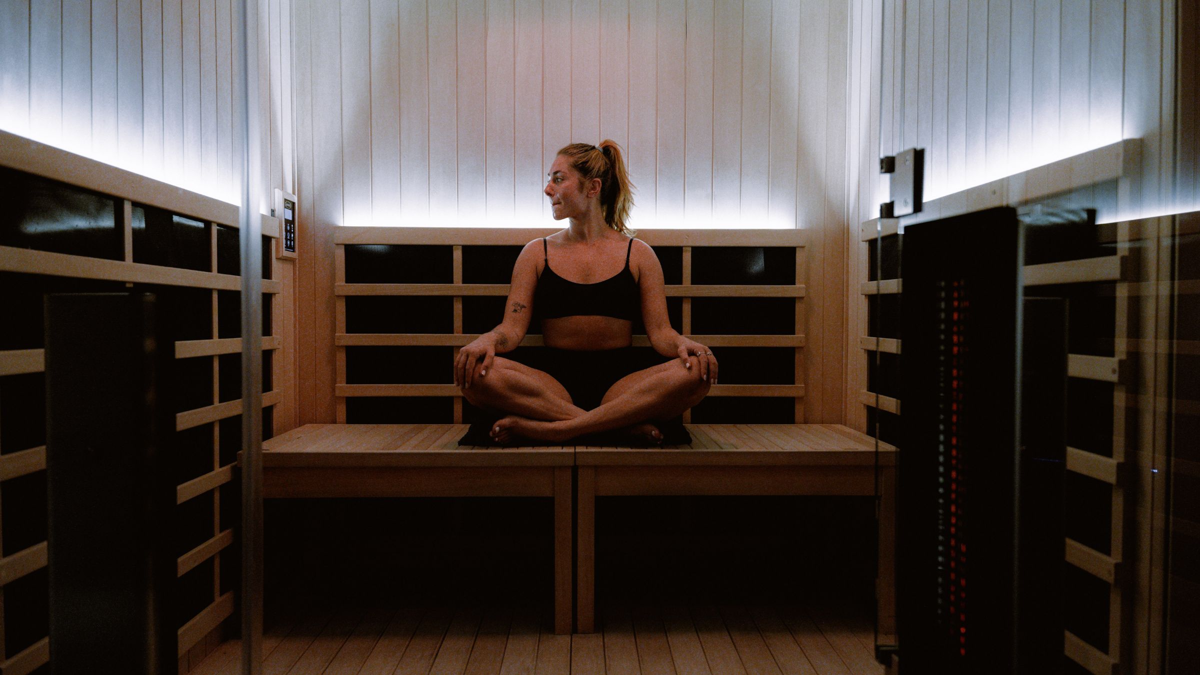Guest seated cross-legged on the bench in an RVIVL infrared sauna